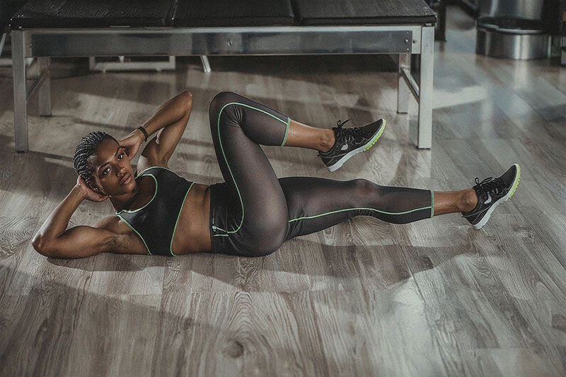 Le Criss Cross en Pilates pour sculpter la taille et les abdos Femme en position Criss Cross Pilates au sol pour renforcer les obliques, sculpter la taille et travailler la sangle abdominale complète